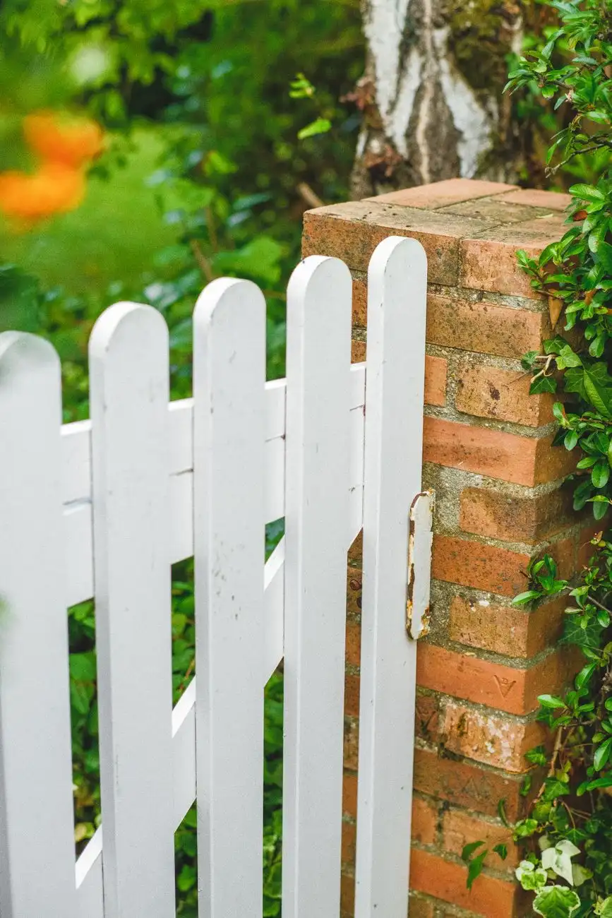 White wooden gate set into a brick garden wall